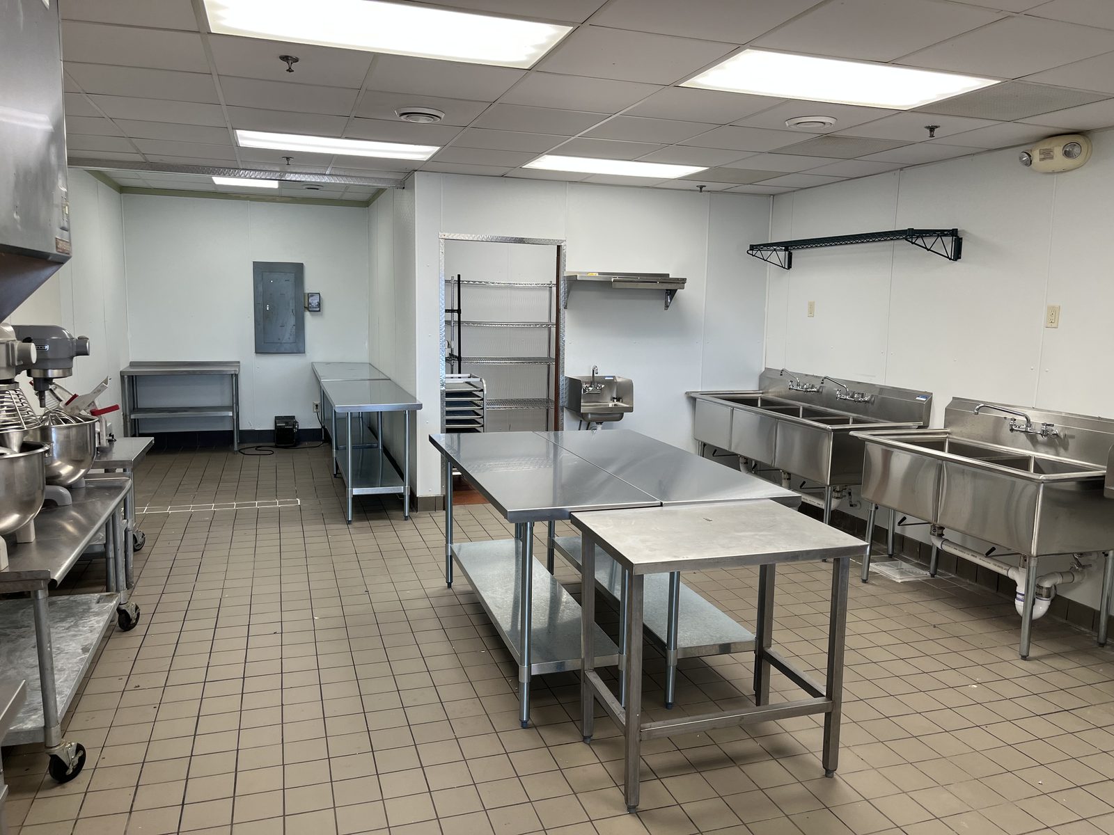 Stainless prep tables, wire shelving, and 2- and 3-compartment sinks